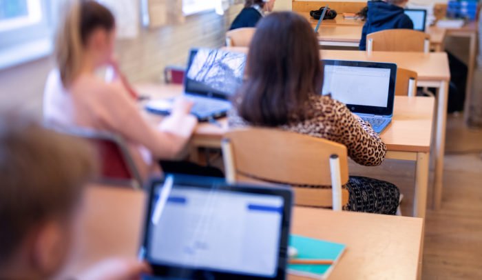 Elever som sitter framför bärbara datorer i ett klassrum