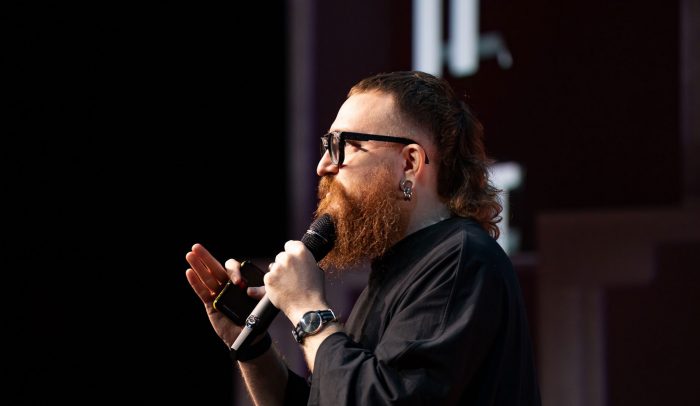 En man med glasögon pratar i en mikrofon.