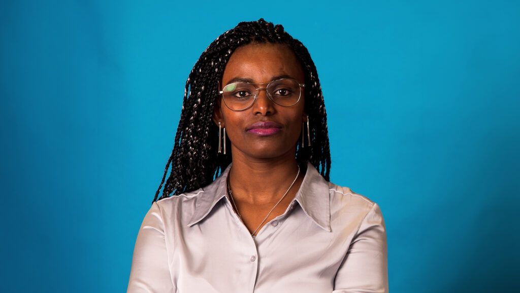 Porträtt av forskaren och huvudtalaren Abeba Birhane mot en blå bakgrund.