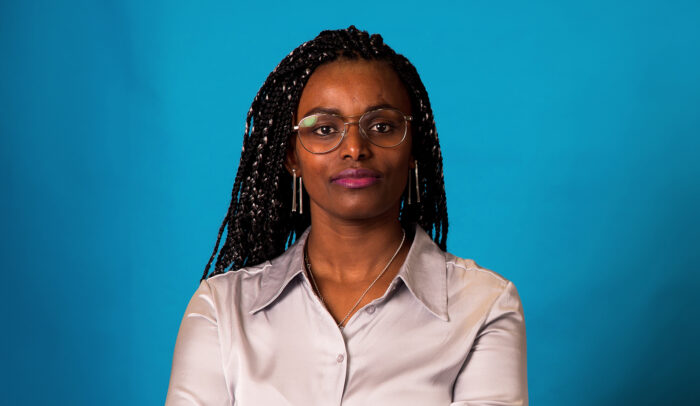 Porträtt av forskaren och huvudtalaren Abeba Birhane mot en blå bakgrund.